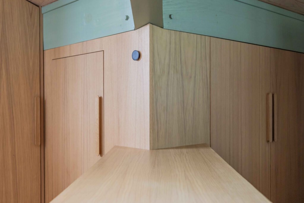 Vue en perspective d'un angle de placard en chêne avec poignées intégrées et détection de mouvement, finition mate