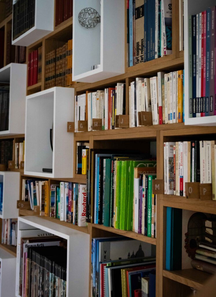 Bibliothèque modulaire contemporaine avec casiers blancs et bois, organisée par sections alphabétiques pour une bibliothèque personnalisée