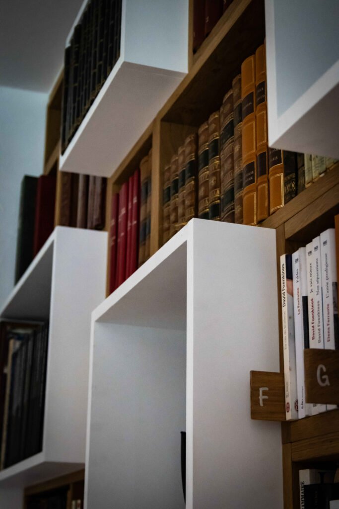 Modules de rangement blancs en saillie contrastant avec des étagères en chêne garnies de livres reliés ancien