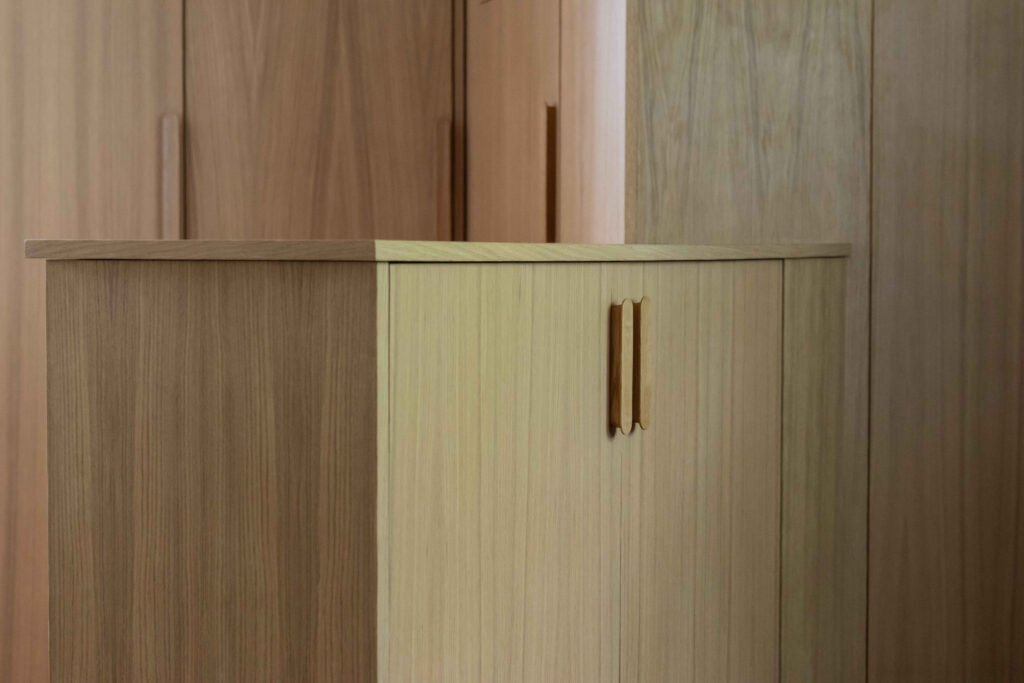 Gros plan sur le plateau et les poignées sculptées d'un meuble en chêne clair, finition mate et minimaliste
