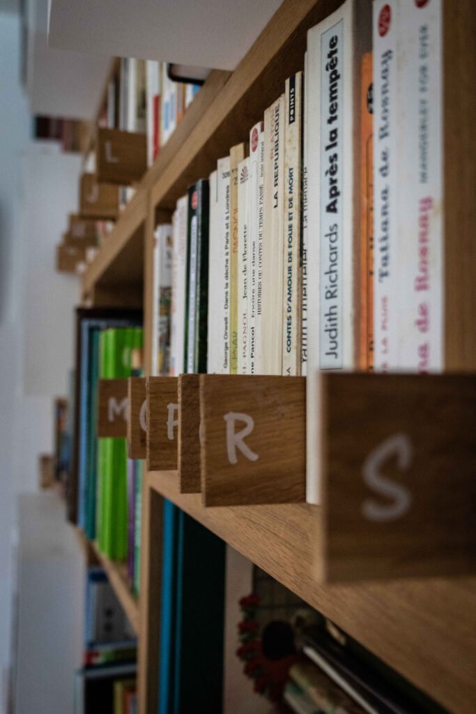 Séparateurs en bois avec lettres peintes M, P, R, S intégrés aux étagères de la bibliothèque sur mesure